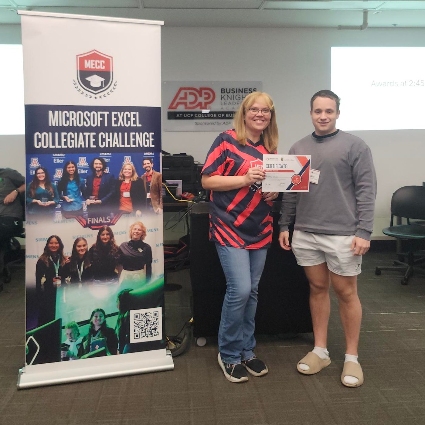 Zach receiving the MECC Regionals certificate beside the Microsoft Excel Collegiate Challenge banner